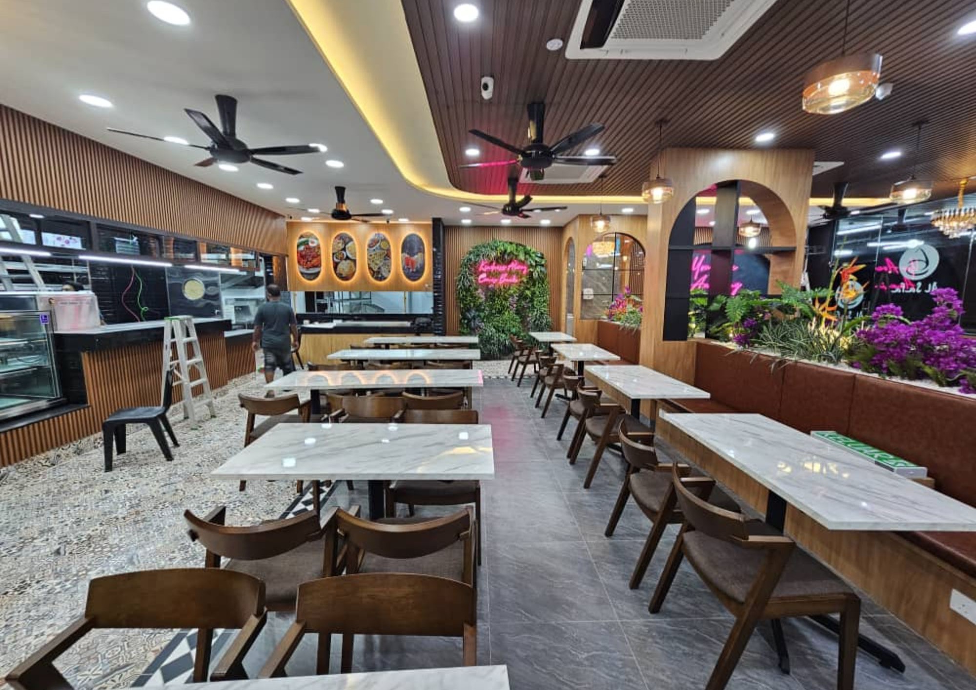 Al-Safa dining hall with marble-top tables, stone feature wall, timber slatted ceiling and greenery planters