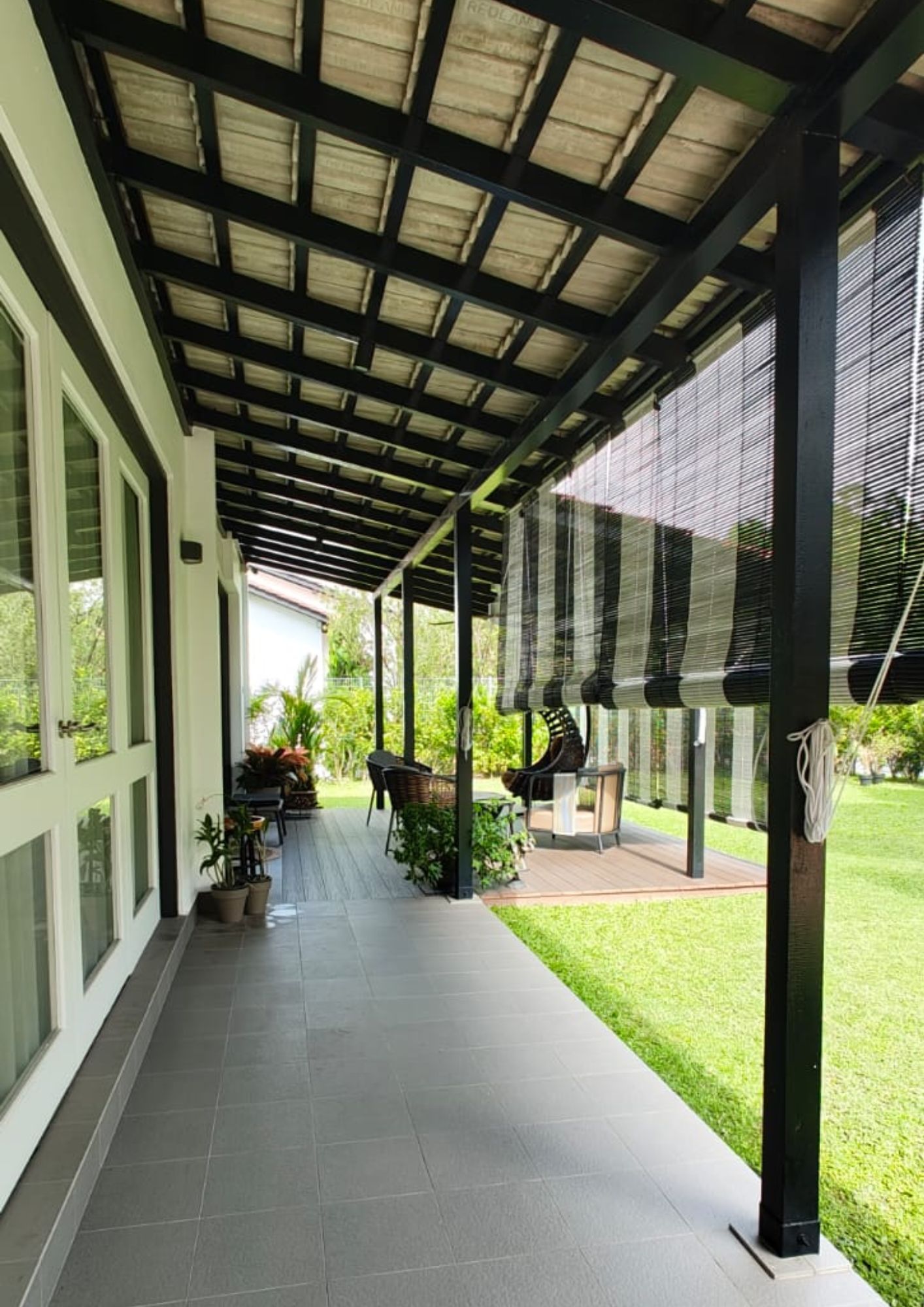 Covered verandah with grey tile floor, black steel pergola frame and garden view