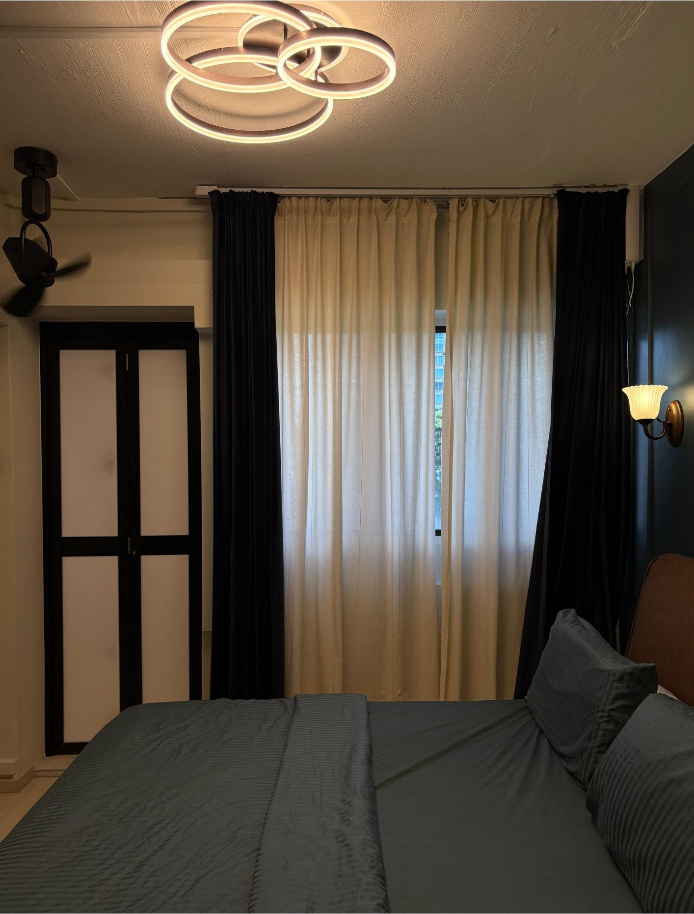 Master bedroom with navy accent wall, black and cream curtains, modern ring ceiling light