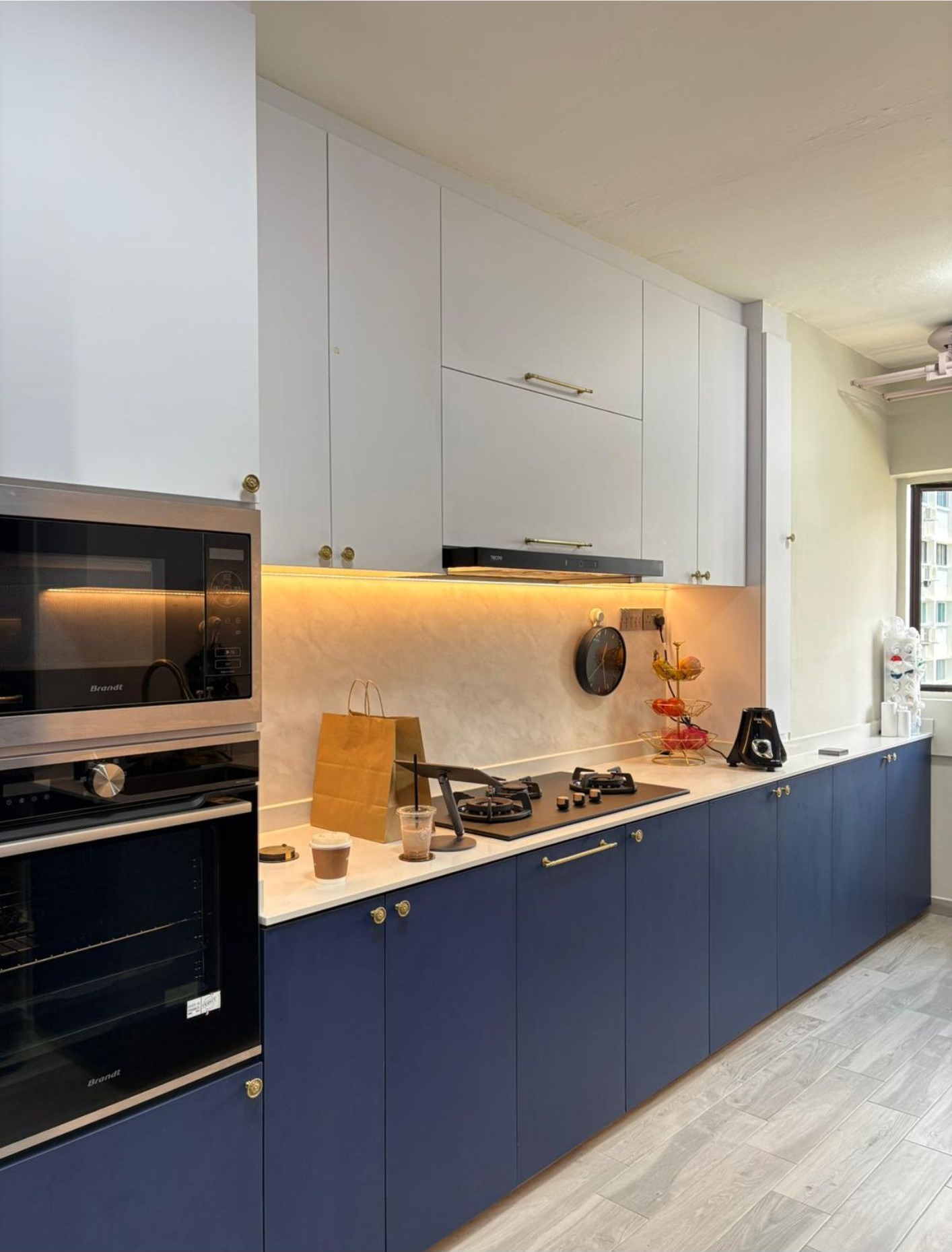 Kitchen full view with navy base cabinets, built-in oven, gas hob and under-cabinet lighting