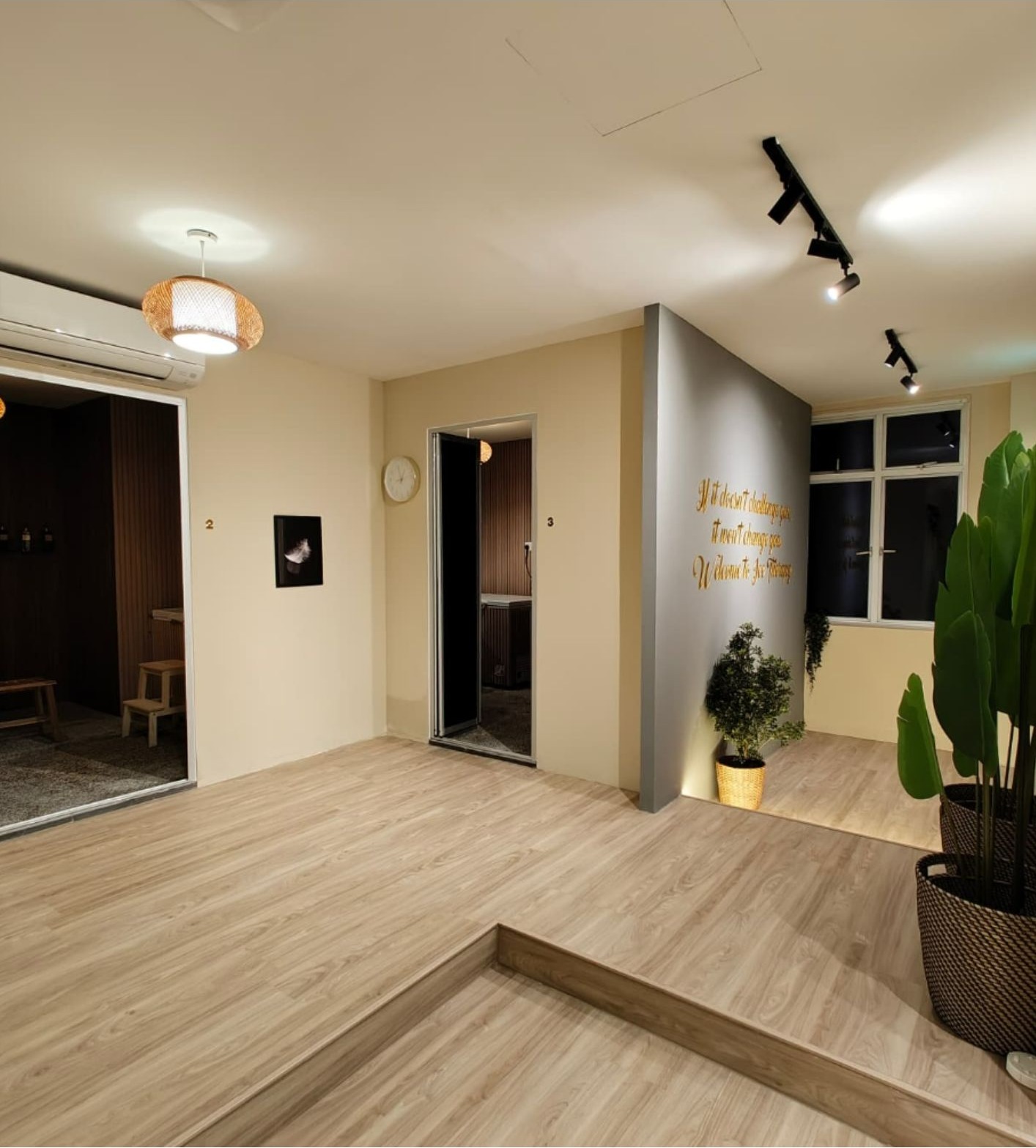 Hallway with grey accent wall, gold motivational text, treatment room doorways and plants
