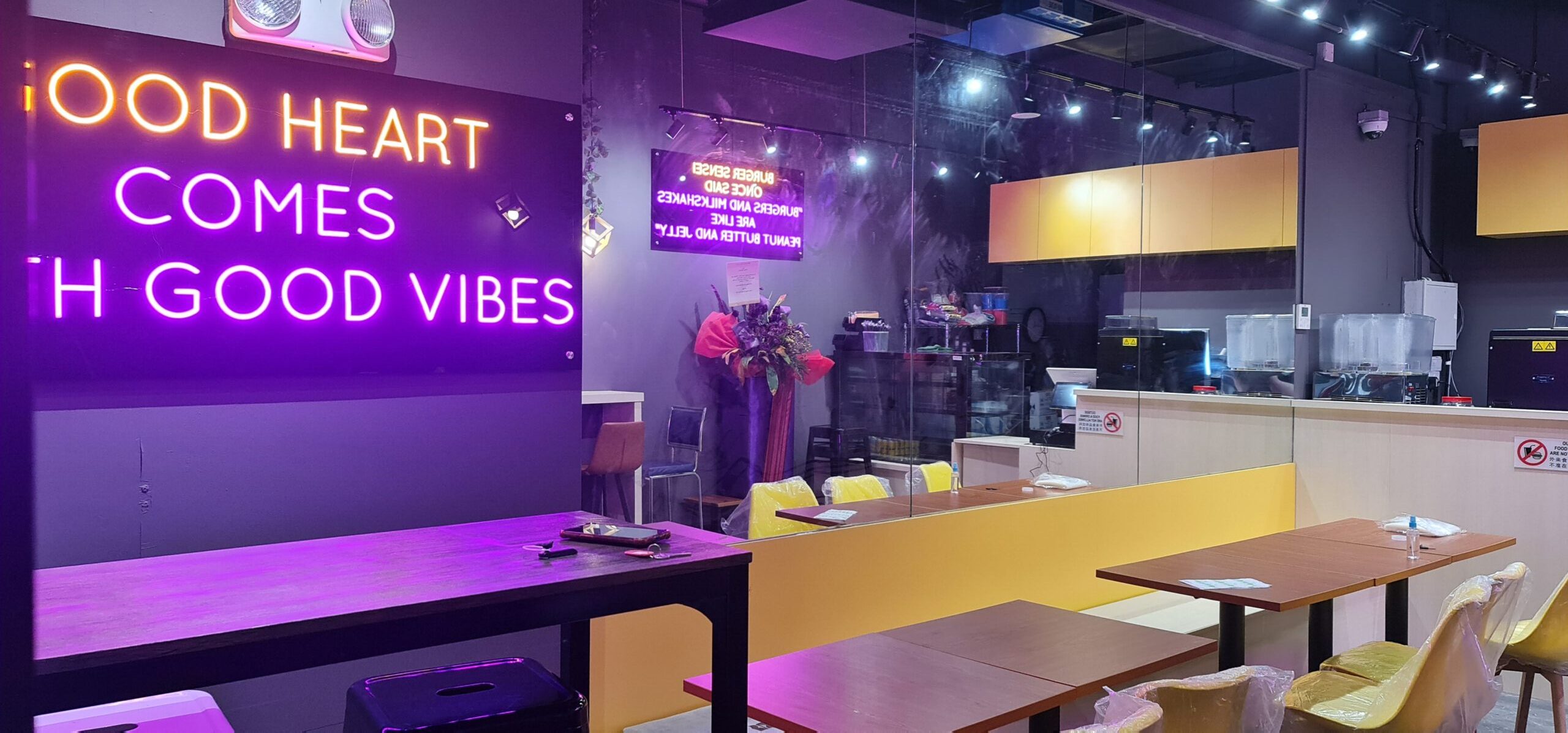 Wally B café interior with neon sign, mustard banquette seating and industrial ceiling at LeQuest Bukit Batok
