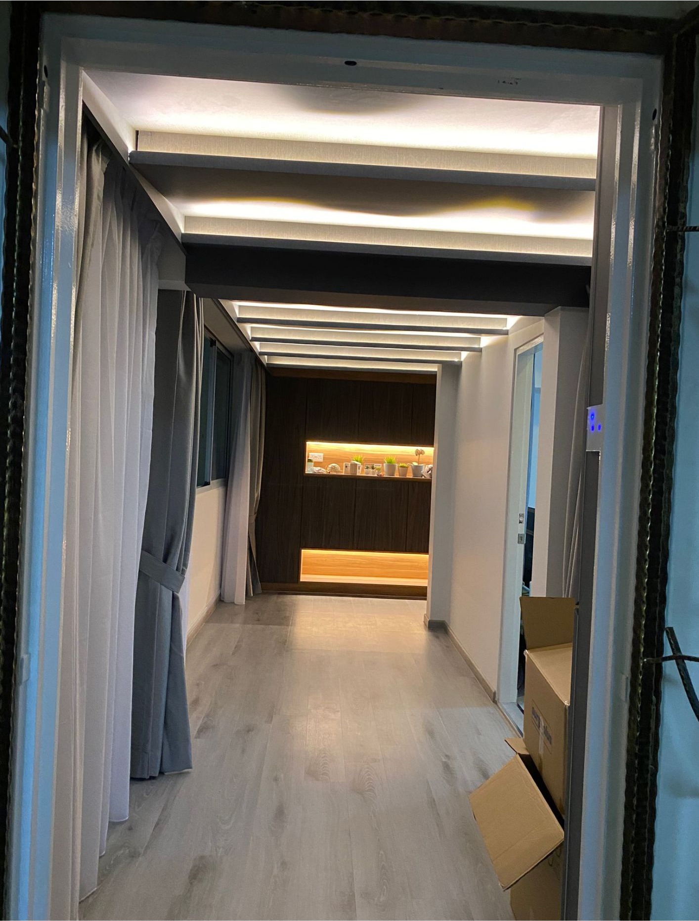 Hallway with LED cove ceiling lights, grey curtains and light timber flooring