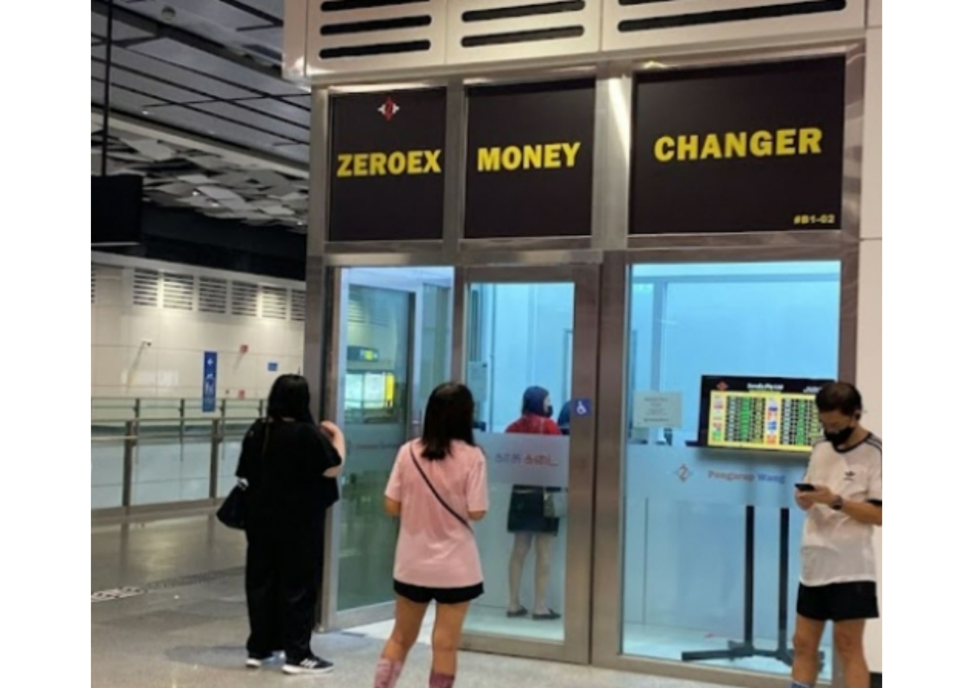 Zeroex Money Changer storefront with customers, glass facade and digital rate display